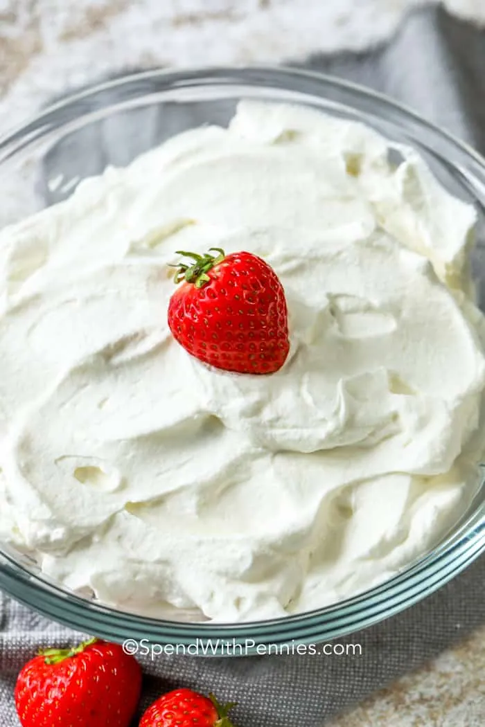 Whipped cream in a glass bowl with a strawberry on top