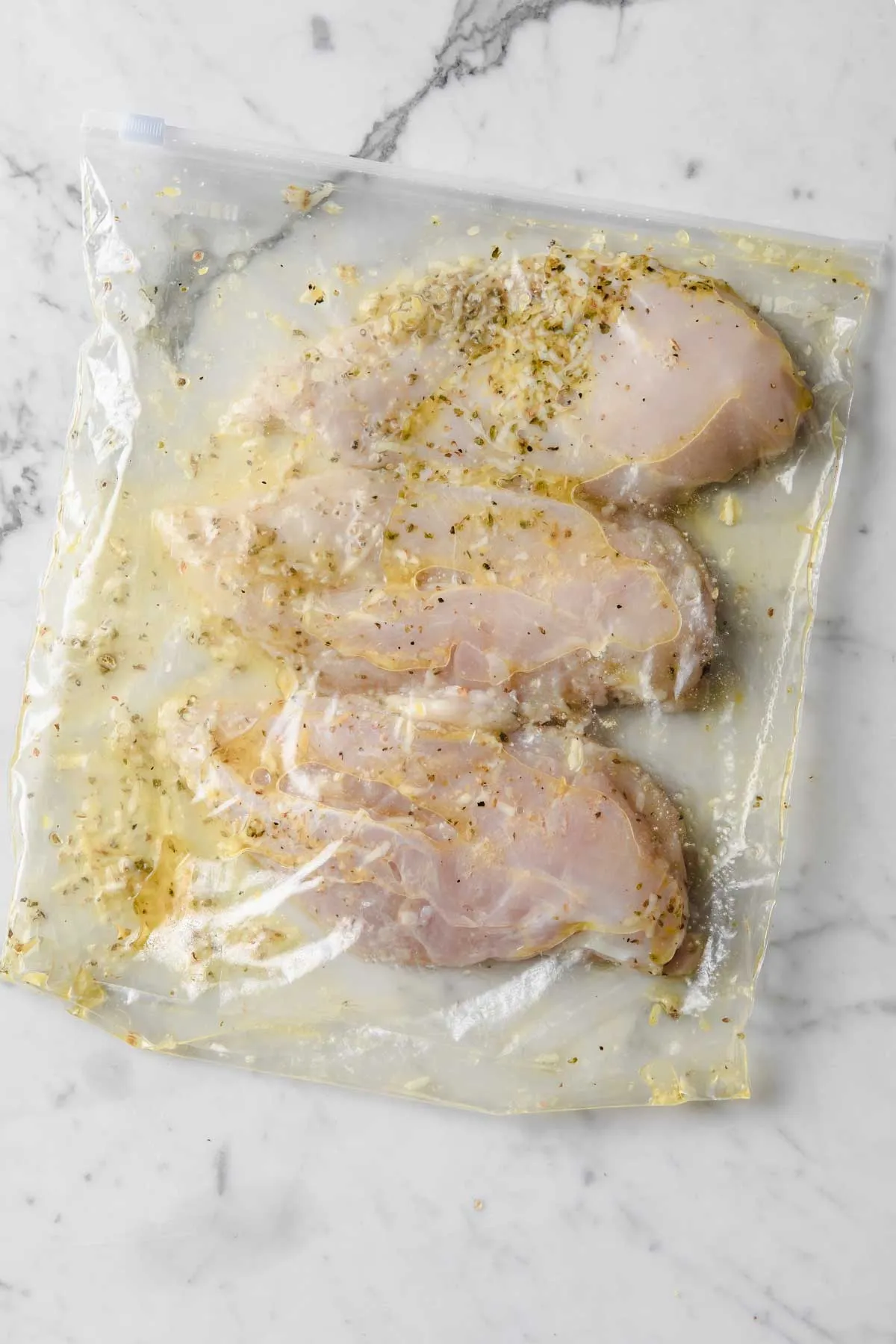 three chicken breasts in lemon marinade in a zip bag